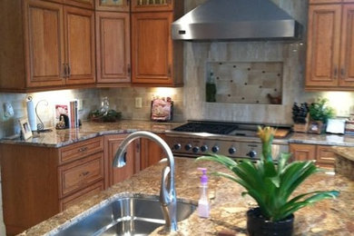 Inspiration for a timeless l-shaped ceramic tile kitchen remodel in Charlotte with a single-bowl sink, raised-panel cabinets, medium tone wood cabinets, granite countertops, beige backsplash, ceramic backsplash, stainless steel appliances and an island