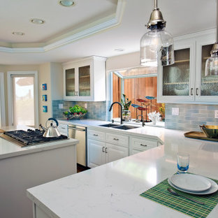 Idee per una cucina a L costiera chiusa e di medie dimensioni con lavello sottopiano, ante con bugna sagomata, ante bianche, top in quarzo composito, paraspruzzi verde, paraspruzzi con piastrelle in ceramica, elettrodomestici in acciaio inossidabile, pavimento in legno massello medio, isola, pavimento marrone, top bianco e soffitto a cassettoni