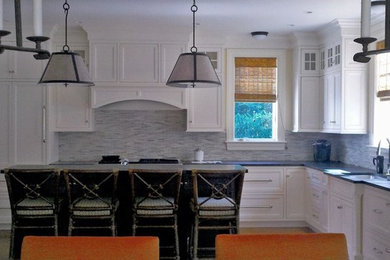 Mid-sized transitional l-shaped light wood floor and beige floor eat-in kitchen photo in Boston with an undermount sink, recessed-panel cabinets, white cabinets, solid surface countertops, gray backsplash, matchstick tile backsplash, stainless steel appliances and an island