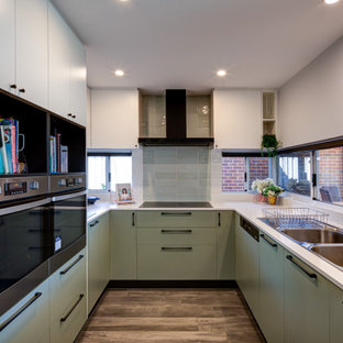 Inspiration for a contemporary u-shaped kitchen in Perth with white benchtop, a double-bowl sink, flat-panel cabinets, green cabinets, stainless steel appliances and brown floor.