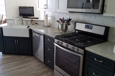 Large farmhouse l-shaped laminate floor and brown floor eat-in kitchen photo in Los Angeles with a farmhouse sink, raised-panel cabinets, blue cabinets, granite countertops, white backsplash, stone tile backsplash, stainless steel appliances, no island and gray countertops
