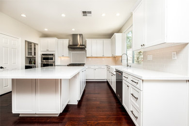 Kitchen pantry - mid-sized transitional u-shaped cork floor and brown floor kitchen pantry idea in Orange County with a farmhouse sink, shaker cabinets, white cabinets, quartz countertops, white backsplash, porcelain backsplash, stainless steel appliances, an island and white countertops