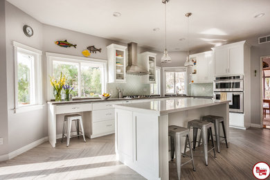 Inspiration for a large transitional l-shaped light wood floor enclosed kitchen remodel in Orange County with an undermount sink, flat-panel cabinets, white cabinets, quartz countertops, green backsplash, stainless steel appliances and an island