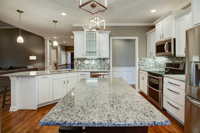 Example of a classic medium tone wood floor eat-in kitchen design in Other with shaker cabinets, white cabinets, an island, an undermount sink, granite countertops, blue backsplash, glass tile backsplash and stainless steel appliances