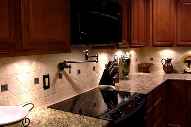 Example of a mid-sized classic u-shaped ceramic tile eat-in kitchen design in Oklahoma City with an undermount sink, raised-panel cabinets, granite countertops, beige backsplash, stone tile backsplash, black appliances and a peninsula