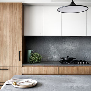 Foto di una cucina contemporanea di medie dimensioni con lavello sottopiano, ante lisce, ante in legno scuro, top in vetro, paraspruzzi grigio, paraspruzzi in lastra di pietra, elettrodomestici neri, penisola e top grigio