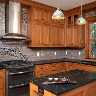 Design ideas for a mid-sized asian l-shaped separate kitchen in Minneapolis with an undermount sink, raised-panel cabinets, medium wood cabinets, soapstone benchtops, grey splashback, ceramic splashback, stainless steel appliances and with island.