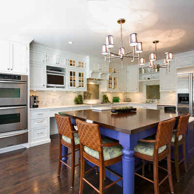 Example of a transitional l-shaped kitchen design in Other with stainless steel appliances, stone tile backsplash, recessed-panel cabinets, white cabinets, white backsplash and wood countertops