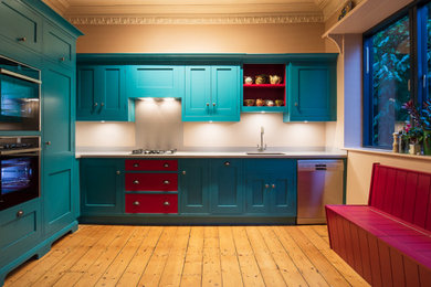 Foto de cocina clásica de tamaño medio con fregadero integrado, puertas de armario azules, encimera de acrílico, salpicadero verde, electrodomésticos con paneles y encimeras grises