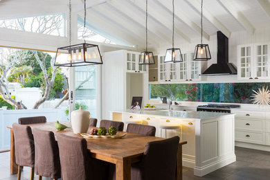 Bild på ett stort funkis kök och matrum, med en rustik diskho, skåp i shakerstil, vita skåp, marmorbänkskiva, fönster som stänkskydd, rostfria vitvaror, travertin golv, en köksö och grått golv