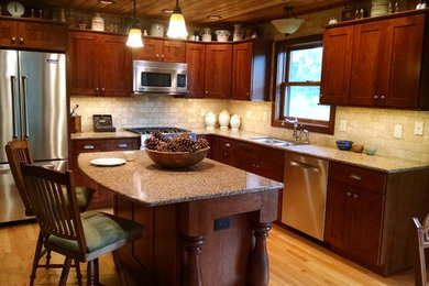 Küche in L-Form mit Unterbauwaschbecken, Granit-Arbeitsplatte, Küchenrückwand in Beige, Küchengeräten aus Edelstahl, hellem Holzboden und Kücheninsel in Minneapolis