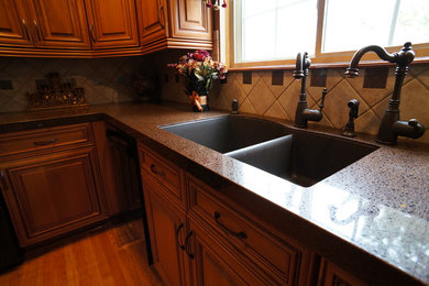 Mid-sized elegant u-shaped light wood floor eat-in kitchen photo in Denver with light wood cabinets, ceramic backsplash and black appliances