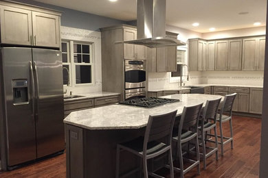 Inspiration for a large traditional l-shaped kitchen/diner in Grand Rapids with a belfast sink, shaker cabinets, grey cabinets, engineered stone countertops, white splashback, porcelain splashback, stainless steel appliances, an island and medium hardwood flooring.