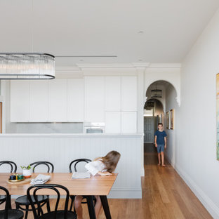 Transitional eat-in kitchen in Sydney with shaker cabinets, white cabinets, white appliances and light hardwood floors.