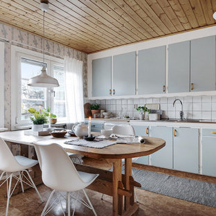 Bild på ett shabby chic-inspirerat kök och matrum, med en integrerad diskho, släta luckor, blå skåp, bänkskiva i rostfritt stål, vitt stänkskydd och brunt golv