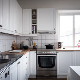 Idéer för ett mellanstort skandinaviskt beige l-kök, med en dubbel diskho, luckor med upphöjd panel, vita skåp, träbänkskiva, vitt stänkskydd, stänkskydd i porslinskakel och rostfria vitvaror