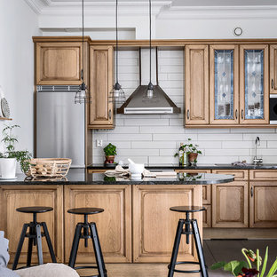 Inredning av ett klassiskt mellanstort linjärt kök med öppen planlösning, med skåp i mellenmörkt trä, granitbänkskiva, rostfria vitvaror, en halv köksö, svart golv, luckor med upphöjd panel och grått stänkskydd