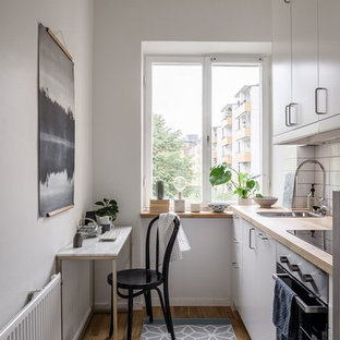 Idéer för ett litet minimalistiskt linjärt kök och matrum, med släta luckor, vita skåp, träbänkskiva, vitt stänkskydd, mellanmörkt trägolv och brunt golv