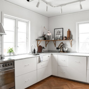 Inspiration för avskilda skandinaviska grått l-kök, med släta luckor, vita skåp, mellanmörkt trägolv, brunt golv, en undermonterad diskho, vitt stänkskydd och rostfria vitvaror