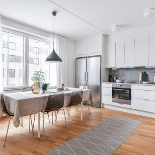 Inspiration för ett funkis beige beige kök, med en undermonterad diskho, släta luckor, vita skåp, grått stänkskydd, rostfria vitvaror, mellanmörkt trägolv och brunt golv