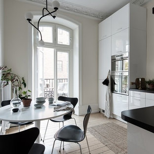 Idéer för skandinaviska svart kök, med en undermonterad diskho, släta luckor, vita skåp, svart stänkskydd, stänkskydd i stickkakel, rostfria vitvaror, ljust trägolv och beiget golv
