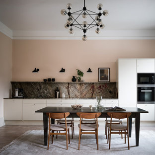 Minimalistisk inredning av ett grå linjärt grått kök och matrum, med släta luckor, vita skåp, grått stänkskydd, stänkskydd i sten, svarta vitvaror, mörkt trägolv och brunt golv