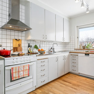 Inspiration för ett avskilt, mellanstort 50 tals grå grått u-kök, med en dubbel diskho, släta luckor, grå skåp, bänkskiva i rostfritt stål, vitt stänkskydd, rostfria vitvaror, mellanmörkt trägolv och brunt golv