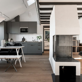Inspiration för ett nordiskt grå linjärt grått kök med öppen planlösning, med släta luckor, grå skåp, vitt stänkskydd, integrerade vitvaror och brunt golv