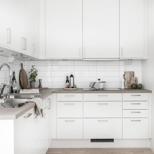 Idéer för att renovera ett nordiskt beige beige l-kök, med en dubbel diskho, släta luckor, vita skåp, träbänkskiva, vitt stänkskydd, rostfria vitvaror, ljust trägolv och beiget golv