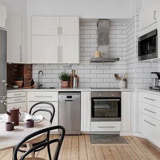 Nordisk inredning av ett vit vitt kök och matrum, med en enkel diskho, luckor med upphöjd panel, vita skåp, vitt stänkskydd, stänkskydd i tunnelbanekakel, rostfria vitvaror, ljust trägolv och beiget golv