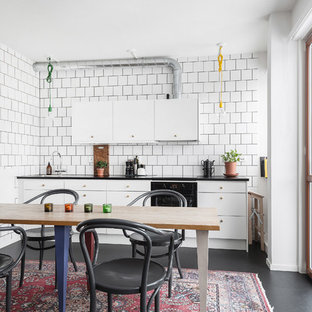 Bild på ett minimalistiskt svart svart kök, med en nedsänkt diskho, släta luckor, vitt stänkskydd, svarta vitvaror och svart golv