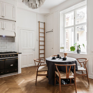 Idéer för att renovera ett skandinaviskt svart svart kök, med luckor med upphöjd panel, beige skåp, vitt stänkskydd, stänkskydd i tunnelbanekakel, svarta vitvaror och mellanmörkt trägolv