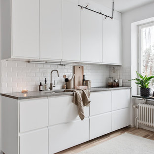 Inspiration för ett nordiskt kök, med släta luckor, vita skåp, bänkskiva i betong, en enkel diskho, vitt stänkskydd, stänkskydd i tunnelbanekakel, ljust trägolv och beiget golv