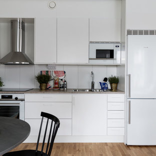 Inspiration för ett funkis grå linjärt grått kök med öppen planlösning, med en undermonterad diskho, släta luckor, vita skåp, vita vitvaror, mellanmörkt trägolv och brunt golv