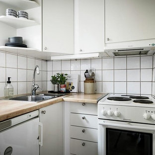 Foto på ett litet nordiskt brun l-kök, med en nedsänkt diskho, släta luckor, vita skåp, träbänkskiva, vitt stänkskydd och vita vitvaror