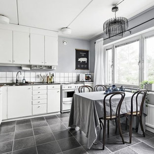 Inspiration för minimalistiska grått kök, med släta luckor, vita skåp, vitt stänkskydd, vita vitvaror och grått golv