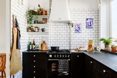 Bild på ett mellanstort skandinaviskt l-kök, med släta luckor, vitt stänkskydd, stänkskydd i tunnelbanekakel och svarta vitvaror