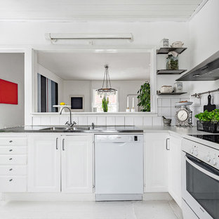 Inredning av ett minimalistiskt litet kök, med vita skåp, bänkskiva i rostfritt stål, vitt stänkskydd, stänkskydd i porslinskakel, vita vitvaror, målat trägolv och vitt golv