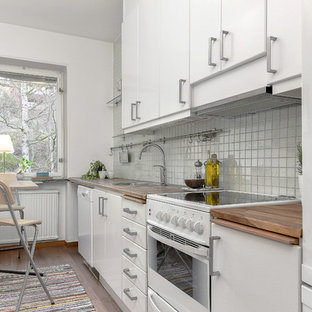 Foto di una piccola cucina lineare scandinava con lavello a vasca singola, ante lisce, ante bianche, top in legno, paraspruzzi bianco, elettrodomestici bianchi, pavimento in legno massello medio, nessuna isola e paraspruzzi con piastrelle in ceramica