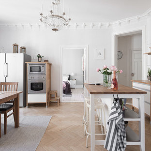 Bild på ett mellanstort minimalistiskt kök och matrum, med öppna hyllor, träbänkskiva, vitt stänkskydd, stänkskydd i porslinskakel, en köksö, rostfria vitvaror, ljust trägolv och beiget golv