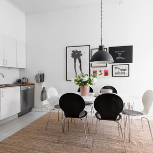 Idéer för ett mellanstort minimalistiskt linjärt kök och matrum, med en nedsänkt diskho, släta luckor, vita skåp, träbänkskiva, vitt stänkskydd, glaspanel som stänkskydd, rostfria vitvaror, målat trägolv och grått golv