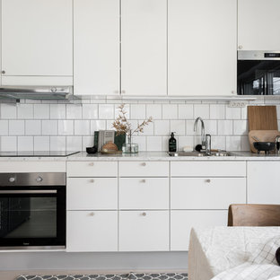 Idéer för att renovera ett mellanstort minimalistiskt grå grått kök, med en nedsänkt diskho, släta luckor, vita skåp, laminatbänkskiva, vitt stänkskydd, stänkskydd i keramik, rostfria vitvaror och ljust trägolv