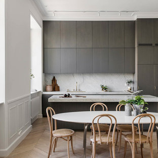 Bild på ett minimalistiskt grå linjärt grått kök och matrum, med en undermonterad diskho, släta luckor, grå skåp, grått stänkskydd, ljust trägolv, en köksö och beiget golv