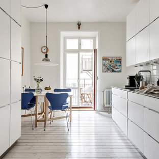 Idéer för ett mellanstort minimalistiskt kök, med släta luckor, vita skåp, bänkskiva i rostfritt stål, stänkskydd i porslinskakel, integrerade vitvaror, ljust trägolv, beiget golv och vitt stänkskydd