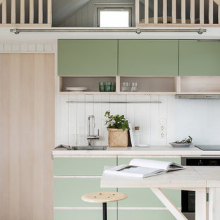Skandinavisk inredning av ett beige linjärt beige kök, med en halv köksö, en nedsänkt diskho, släta luckor, gröna skåp, träbänkskiva och vitt stänkskydd