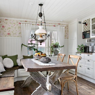 Photo of a country l-shaped eat-in kitchen in Gothenburg with a farmhouse sink, raised-panel cabinets, white cabinets, white splashback, subway tile splashback, medium hardwood floors, a peninsula and brown floor.