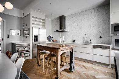 Exempel på ett minimalistiskt linjärt kök, med marmorbänkskiva, rostfria vitvaror, mellanmörkt trägolv och en köksö