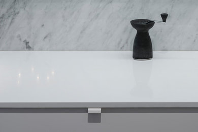 Imagen de cocina minimalista de tamaño medio con encimera de cuarzo compacto, salpicadero de mármol y encimeras blancas