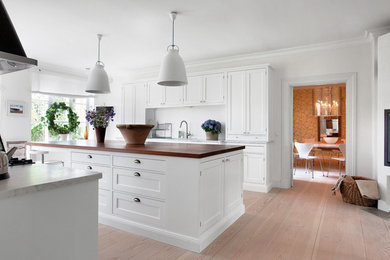 Exempel på ett klassiskt kök, med luckor med infälld panel, vita skåp och en köksö