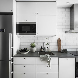 Inspiration för minimalistiska grått kök, med släta luckor, vita skåp, bänkskiva i betong, vitt stänkskydd, en nedsänkt diskho och rostfria vitvaror
